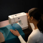 Person using a sewing machine on a dark background