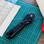 Black rotary cutter on a green cutting mat with fabric and ruler