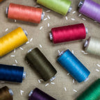 Spools of colorful thread on a textured fabric background