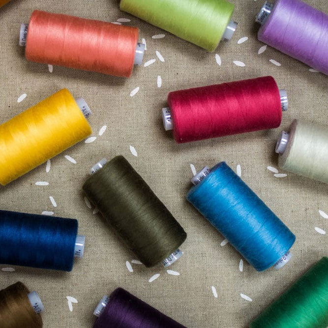 Spools of colorful thread on a textured fabric background