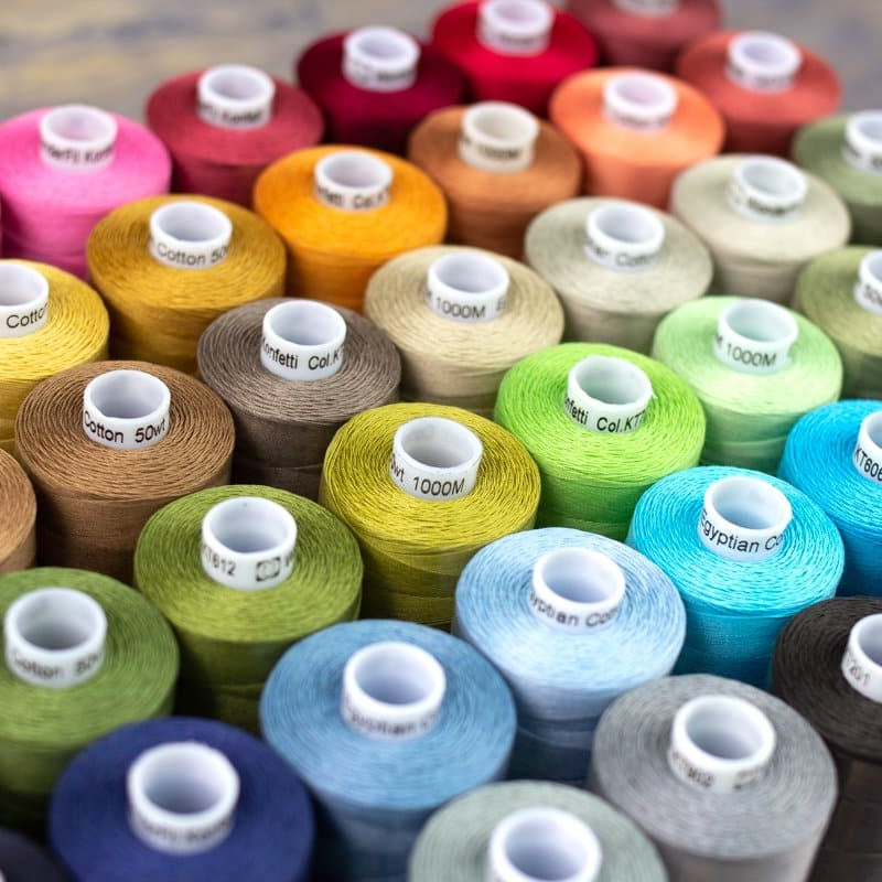 Assorted spools of thread in various colors on a wooden surface
